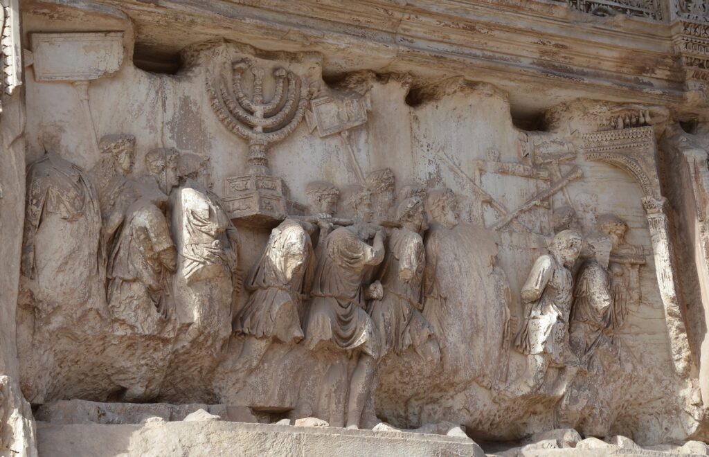 This relief from the Arch of Titus in Rome shows the emperor Titus in his chariot (right), behind his troops in the triumphal parade, accompanied by a (now headless) youth representing the citizens of Rome.